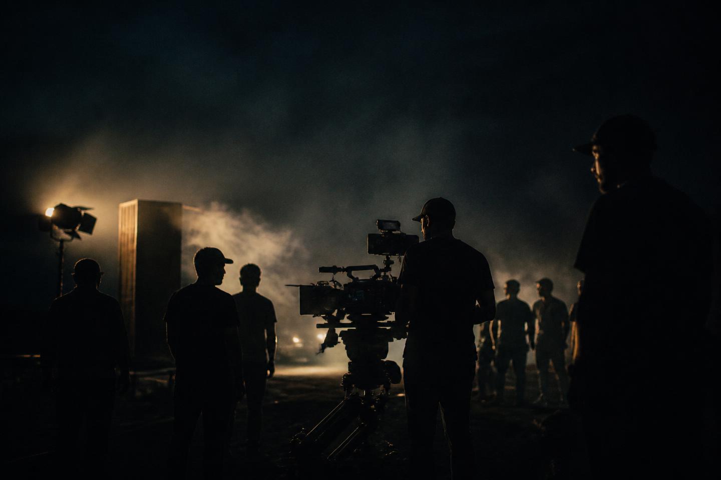 Film crew silhouetted around a cinema camera on a night set